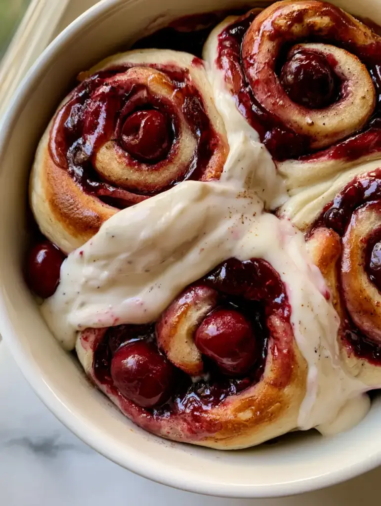 Smartphone photo of freshly baked cherry rolls with vanilla bean flecks in the cream cheese frosting and a dusting of cinnamon.