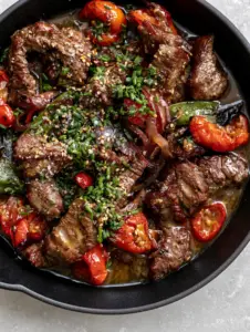 Close up of seared beef bites with glistening butter sauce and sesame seeds in a skillet. (easy recipe)