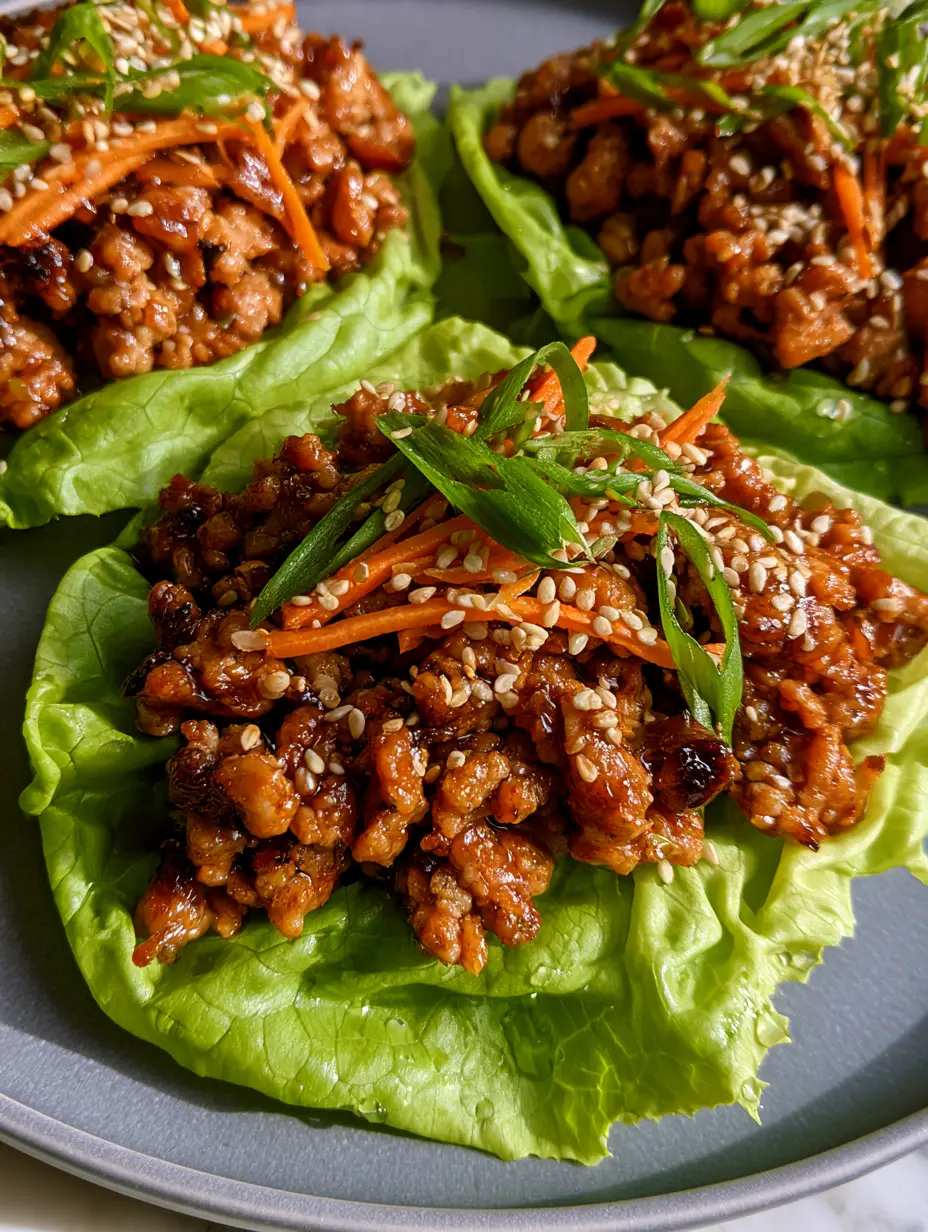 A macro smartphone photo of three vibrant, crisp butter lettuce cups overflowing with savory seared ground turkey. (ground turkey lettuce wraps)