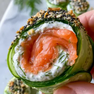 Extreme close-up of smoked salmon cucumber rolls featuring translucent cucumber ribbons and vibrant orange-pink salmon.