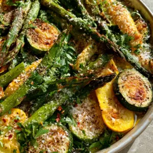 Top-down view of vibrant green asparagus and golden zucchini rounds on a grey stone background. (Asparagus with Zucchini and Squash)