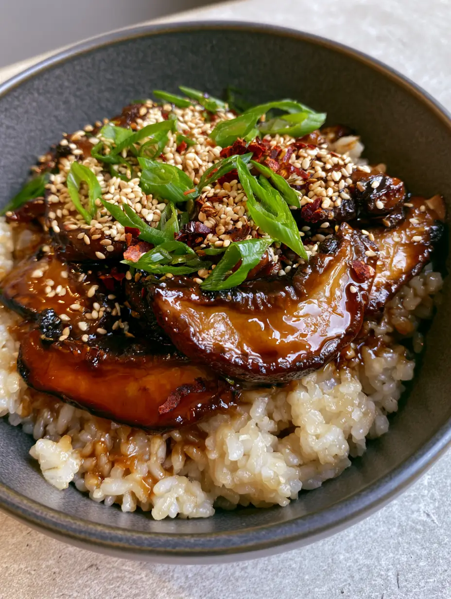 Close-up of deeply seared shiitake mushrooms with charred edges and a thick amber glaze (mushrooms with sticky rice).